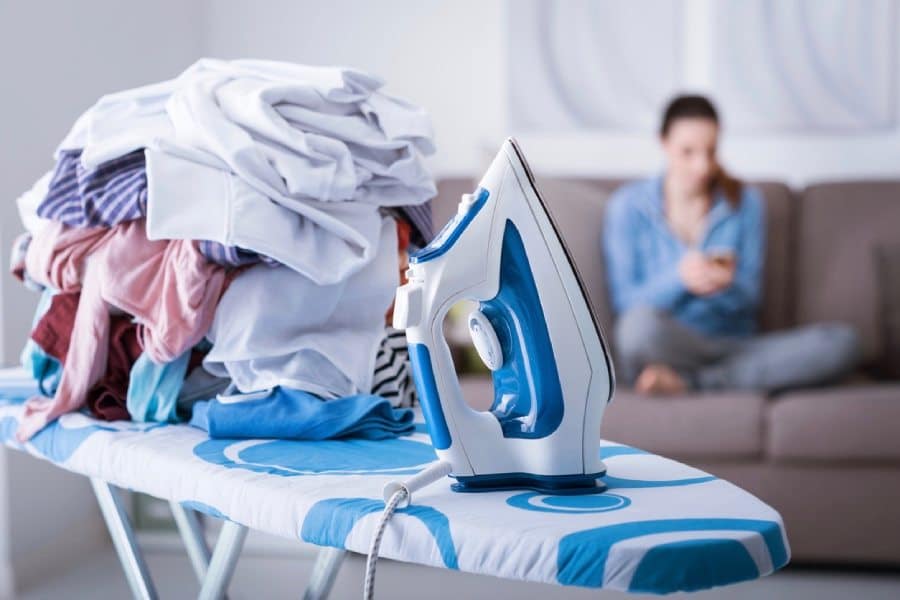 Jeune femme qui procrastine devant son linge à repasser. La sophrologie pourrait l'aider.